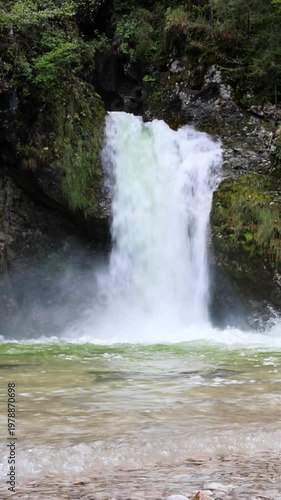 beautiful scenic small waterfall in forest next to farm river and bike trail in bohinj slovenia europe (stunning landscape julian alps alpine mountains scenery) trees woods hiking hike path trail