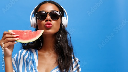 Woman Enjoys Watermelon While Wearing Headphones and Sunglasses in Front of B...