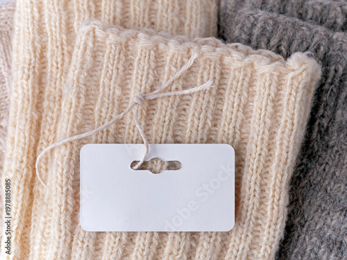 A blank paper tag on a string attached to a folded woolen garment.