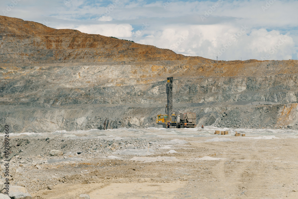 Fototapeta premium Drilling rig operating in large open pit mine landscape, gold mining industry