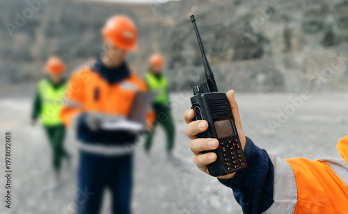 Foto Worker holding walkie talkie with crew at open pit quarry