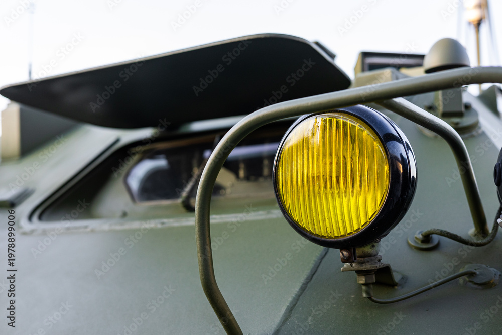 Fototapeta premium Military equipment and army equipment.. Industrial armored vehicle headlight showing wear and protective features. Detailed view of combat vehicle headlight emphasizing ruggedness