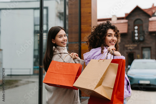 Foto Happy friends leaving store after successful shopping