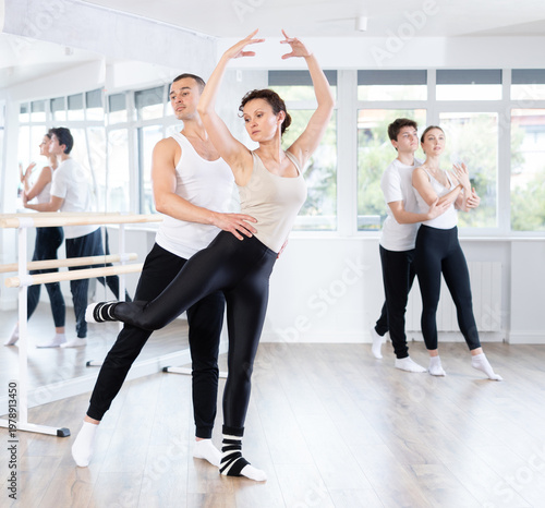Young man and adult woman perform paired ballet dance in studio