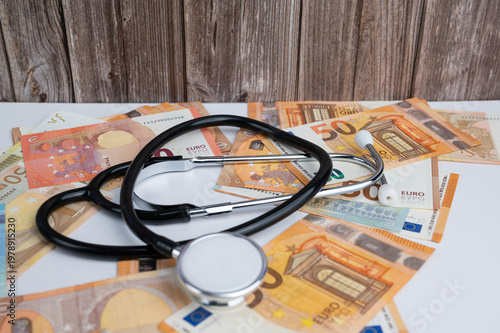 A stethoscope on Euro banknotes show financial burden of medical care and insurance