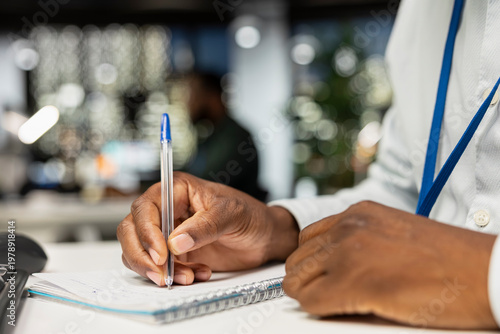 Cuadro en lienzo Close up of black businessman transcribing key points on notebook after hours