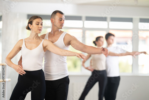 Young man and young woman perform paired ballet dance in studio