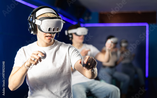 Obraz na płótnie In dark hall of entertainment center, young guys and girls talking about spending time in virtual game