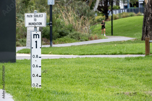 Fotografi Flood level marker indicating path subject to inundation in a public park in Maribyrnong Australia