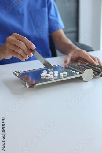 Pharmacist Counting White Medicine Pills on Stainless Steel Counting Tray in Pharmacy.