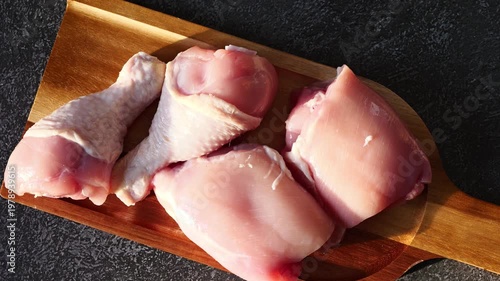 Fresh chicken pieces ready for cooking on a wooden cutting board in bright kitchen light