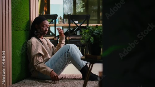 Unhappy black woman in depressive mood suffering from stress and frustration, sitting silently on the floor in hallway, mental illness and emotional breakdown. Sad girl in sorrow, darkness.