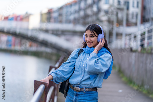 Fotografie Young woman enjoying music with headphones outdoors smiling