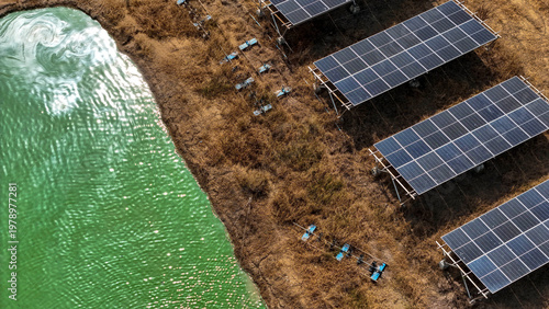 Fotografi Aerial view of solar panels installed near a water body with maintenance equipme