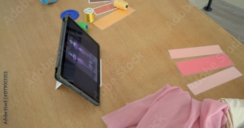 Camera panning across tabletop, revealing tablet playing plus pink swatches, scissors, tape, boxes