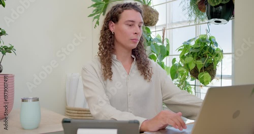 Vertical video: Typing on laptop, worker in light shirt switching to notebook for notes at home