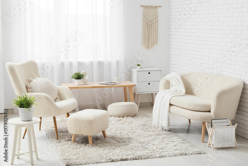Interior of living room with comfortable armchairs, coffee table and ottoman