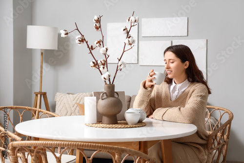 Young woman drinking tea at...