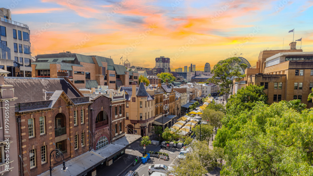 Fototapeta premium 31 March 2026 Historical Buildings at Sydney Rocks area with view of the Harbour Bridge in the Background. The Rocks is the Original Landing place of Captain Cook on Sydney Harbour and Circular Quay i