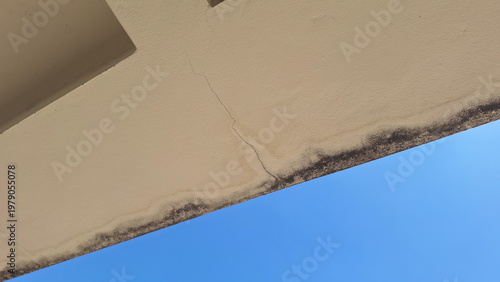 Cracked Concrete Eave with Water Stains and Mold Accumulation on Exterior Wall