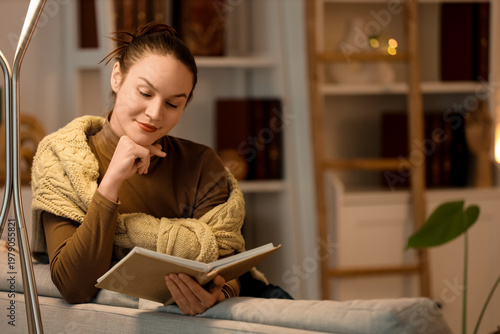 Young woman reading book on...