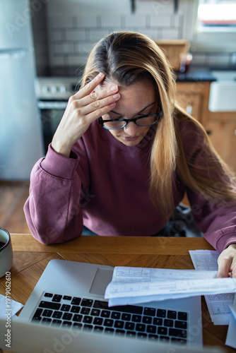 Cuadro en lienzo Stressed woman reviewing bills at home kitchen table