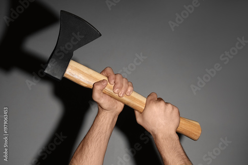 Hands with ax on grey backg...