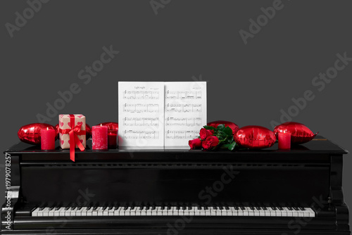 Piano with note sheets, burning candles, roses and balloons on dark background. Valentine's Day celebration