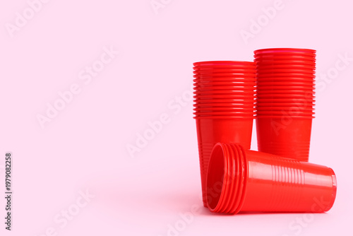 Red plastic cups on pink ba...