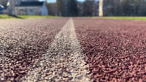 A bottom view showing the markings of a running track, the surface texture of a sports stadium, and a training background