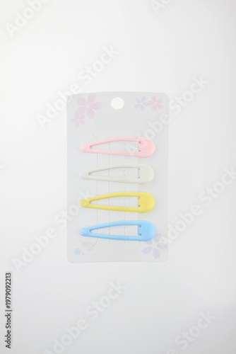 Soft colors pastel hair clips on card with floral design include pink, white, yellow, and blue. Clean background highlights product simplicity, decorative retail packaging isolated on white background