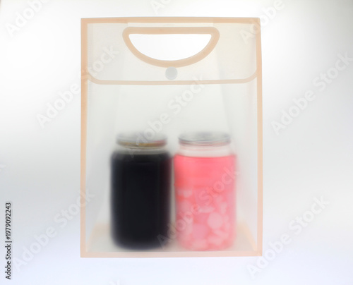 Clear bag holds two glass jars. One jar contains coffee. The other contains colorful pink fruit drink ice.  Transparent frosted plastic bag softly blurs the contents, isolated on white background. 