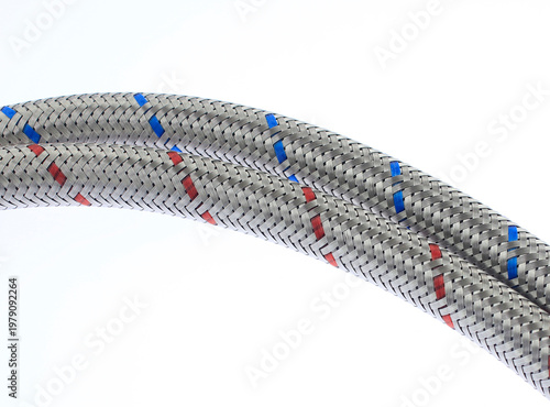Metallic braided hose with red and blue markers. Coil rests against clean white background. Industrial or mechanical applications highlighted. Precise, professional design appeals to technical buyers.