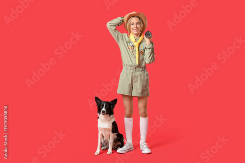 Fotografía Boy scout with cute Border Collie dog and flashlight on red background
