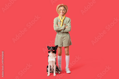 Quadro em tela Boy scout and cute Border Collie dog with flashlight on red background