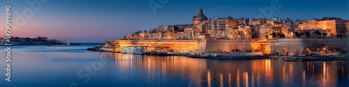 Calm waters reflect warm city lights at dusk