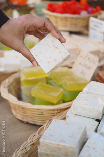 Φωτογραφία Hand selecting handmade soap at a market