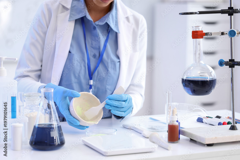 Fototapeta premium Young African-American female chemist with mortar and Petri dish working in lab, closeup