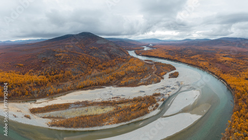 Autumn landscape. Aerial view of the river valley and mountains. Top view of the river and forest. Yellow larch trees. Beautiful northern nature. Ola river, Magadan Region, Siberia, Far East of Russia