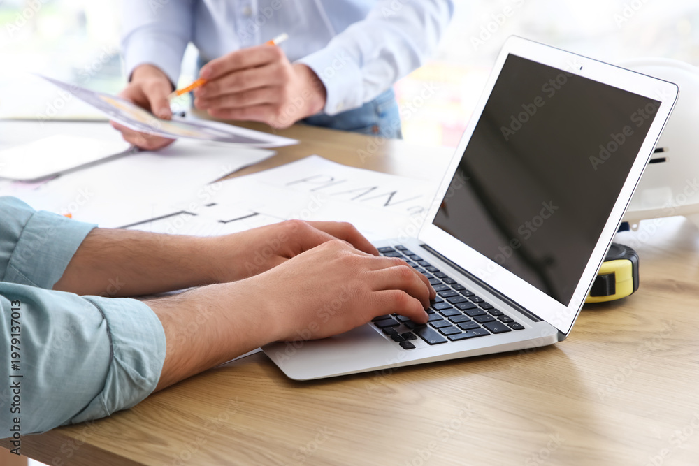 Fototapeta premium Male constructor working with blank laptop at table in office, closeup
