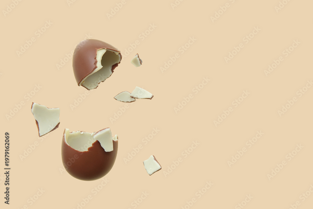 Naklejka premium Broken chocolate egg flying on beige background