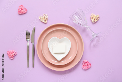 Beautiful table setting with blank card and decorative hearts on lilac background. Valentine's Day celebration