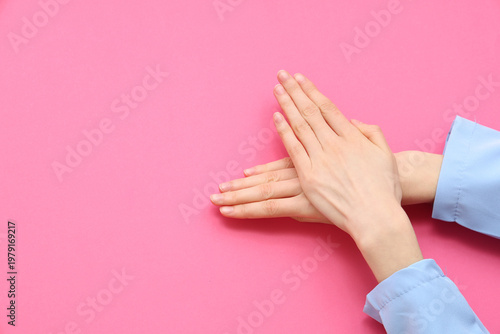 Female hands showing heart gesture on pink background