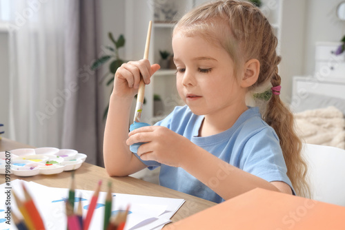 Cute little girl painting a...