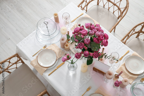 Beautiful table setting with pink roses and candles for wedding celebration in room, top view