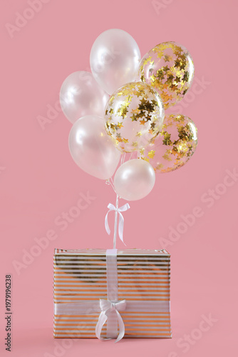 Wrapped gift box with bunch of floating balloons on pink background