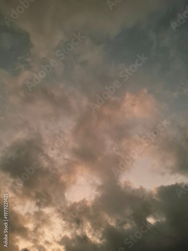 Moody cloudscape at dusk with dramatic dark clouds illuminated by soft warm sunset light