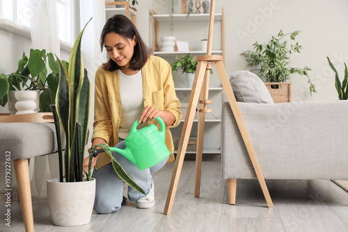 Young woman watering plant ...