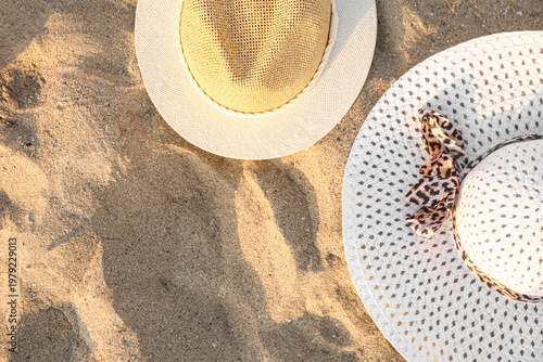 Stylish straw hats on sand