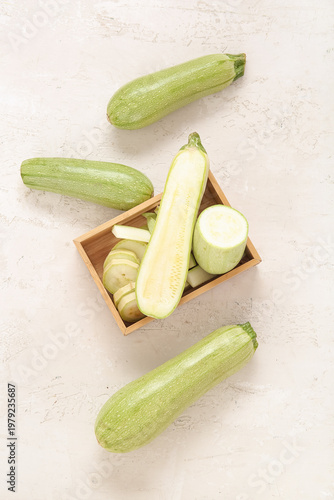 Wooden box with fresh green zucchini on light background